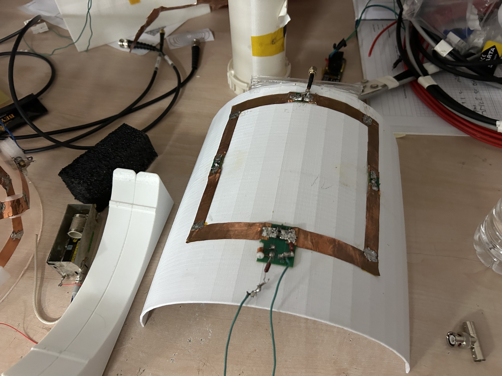 Rectangular copper receive loop on a white curved former with a small circuit board