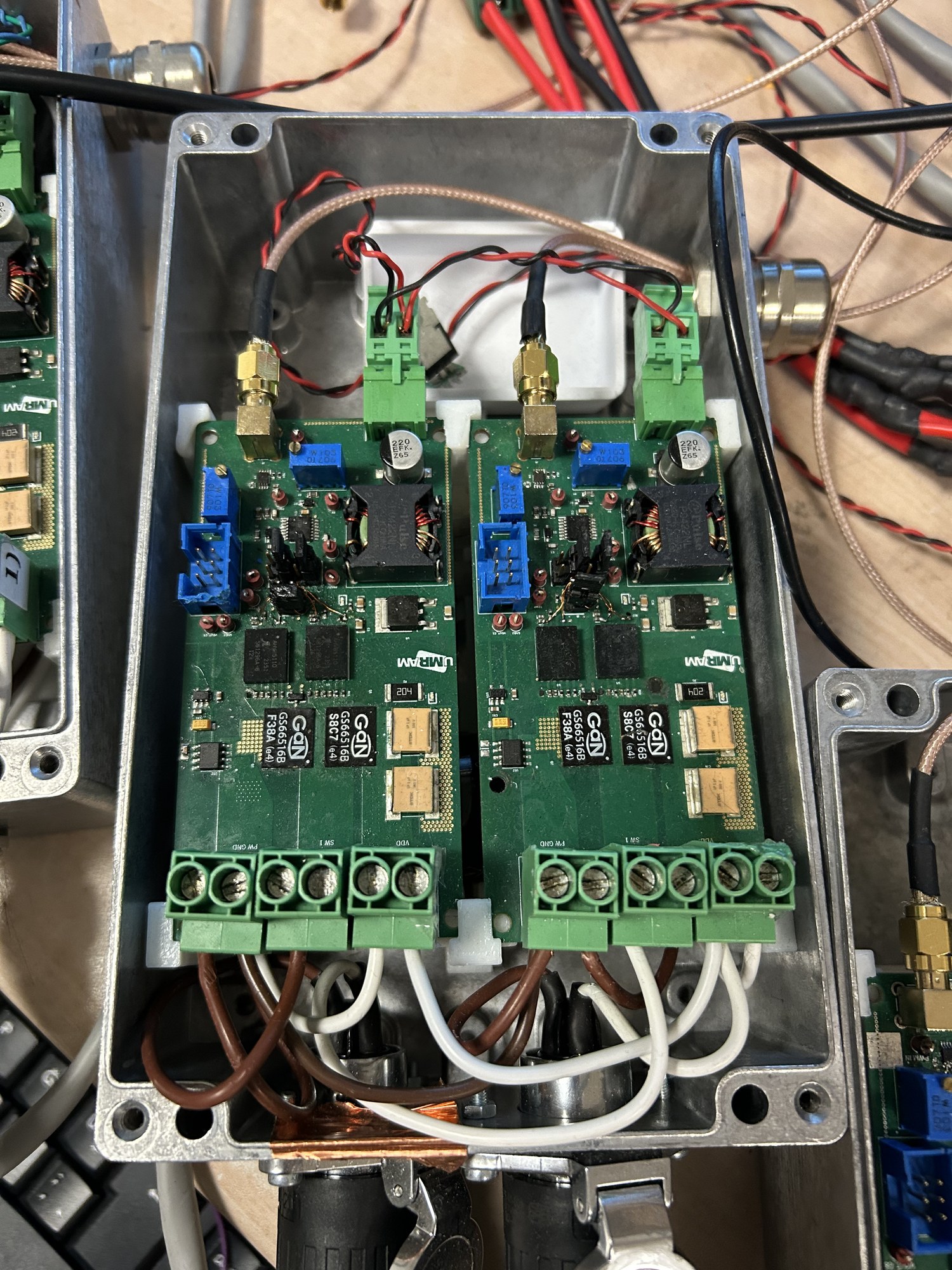 Two green amplifier circuit boards with GaN transistors inside an aluminum enclosure