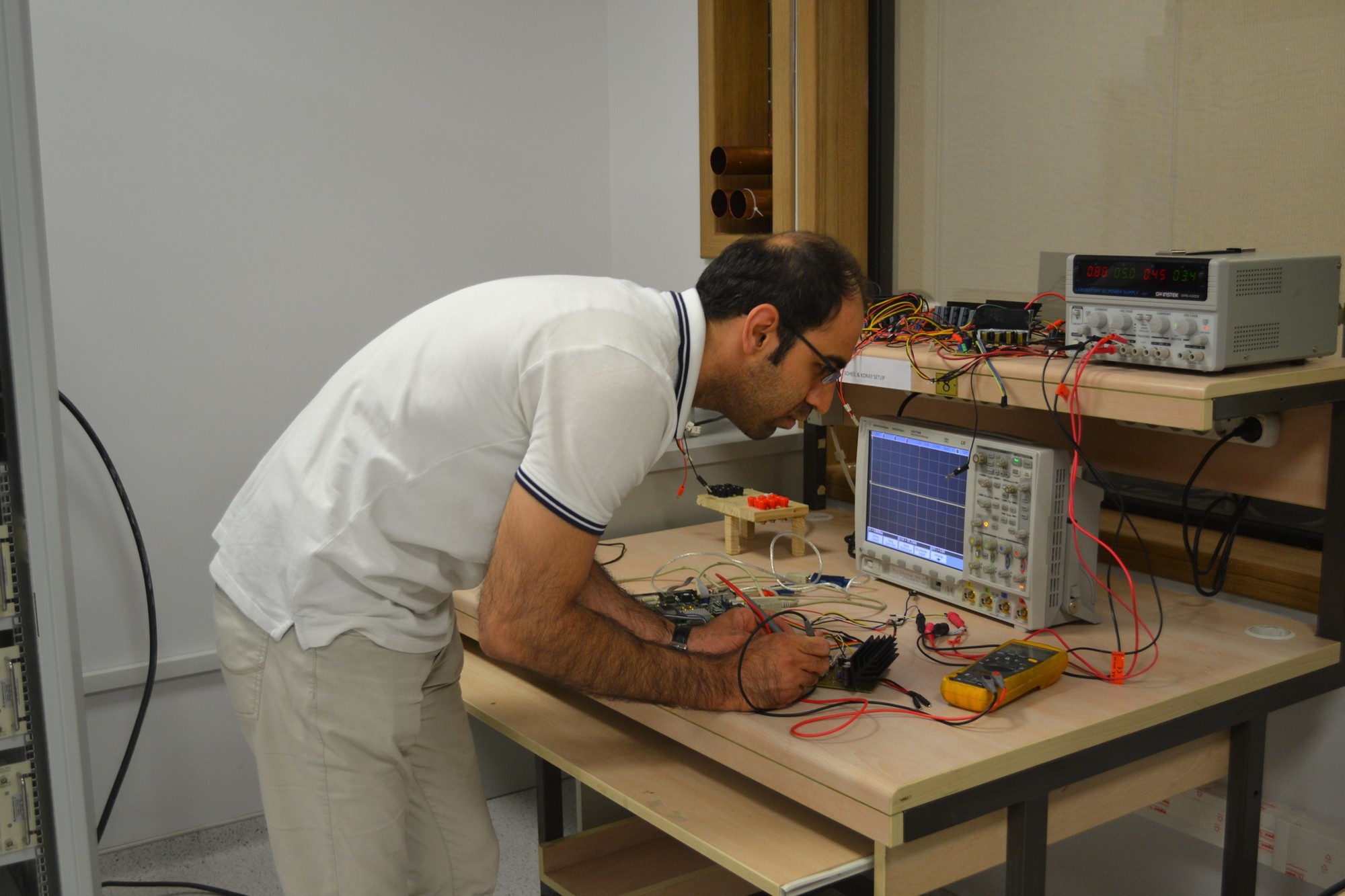 A researcher probing an amplifier board at the electronics bench